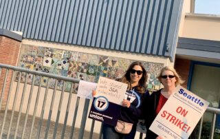 Picture of PROTEC17 Communications Director Deidre at Wedgwood Elementary with a teacher. They are holding PROTEC17 signs and Seattle Education Association on strike signs.