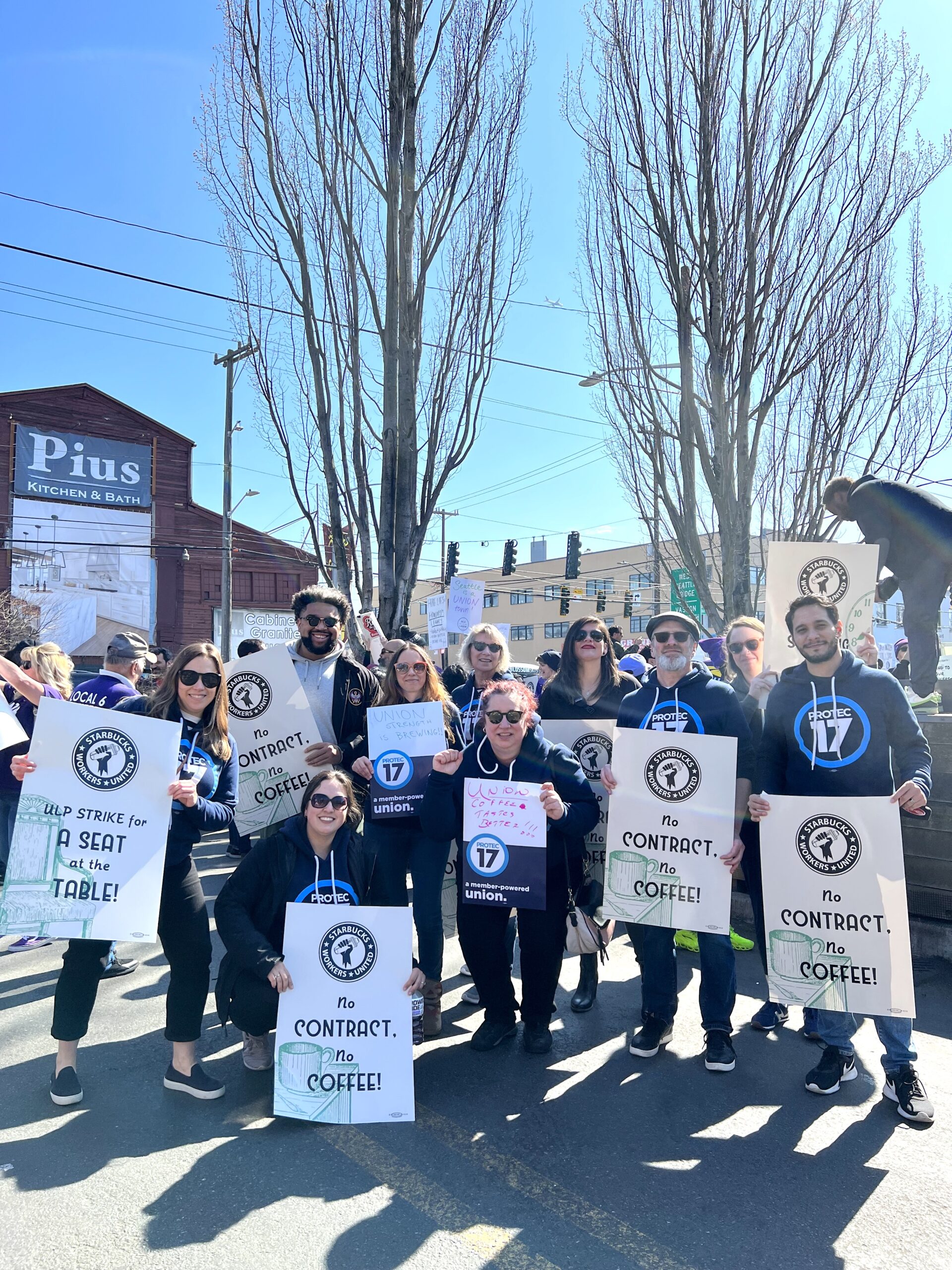 Picture of PROTEC17 staff holding signs of support for Starbucks workers and raising their fists in solidarity.