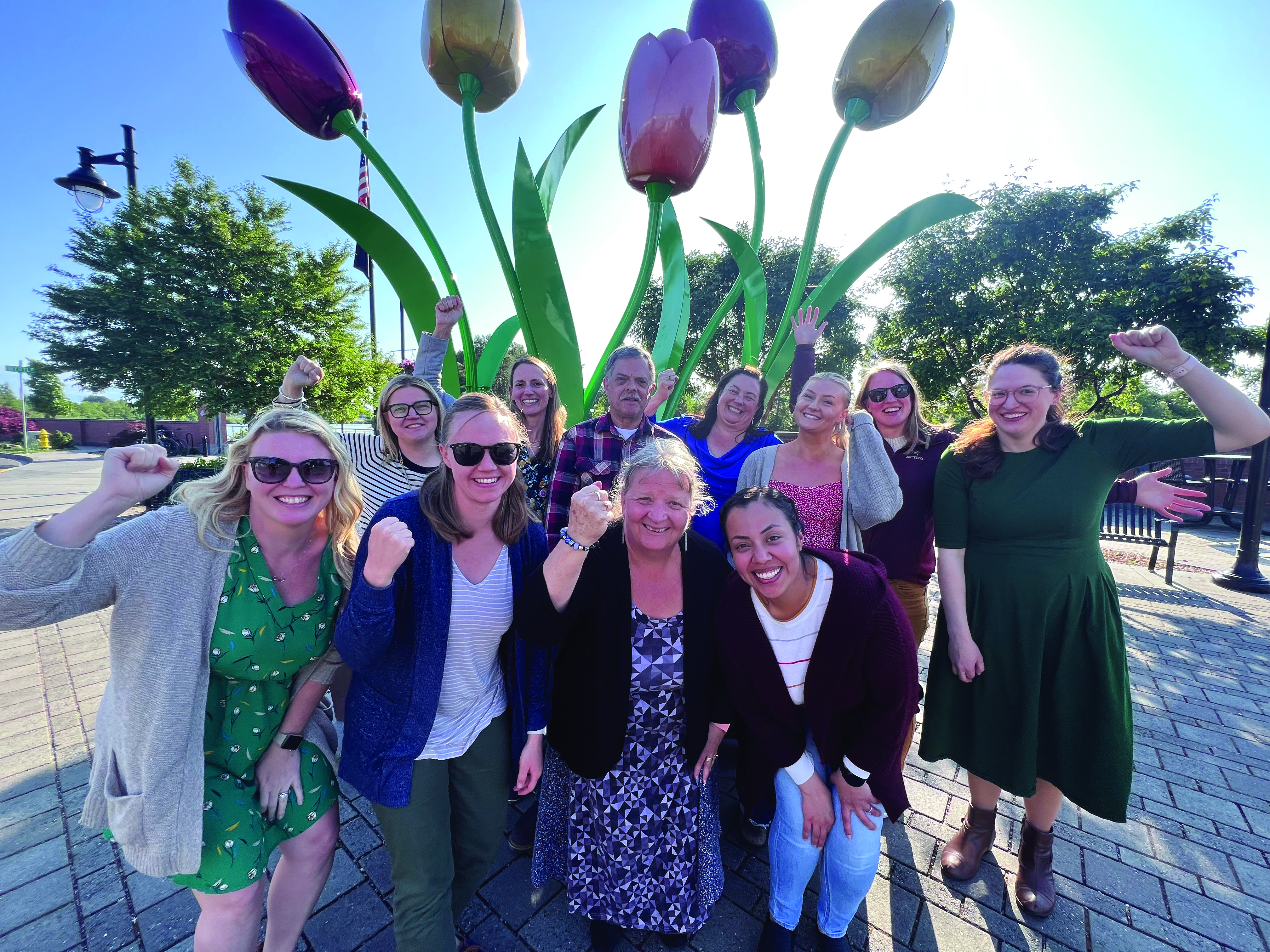 Picture of new PROTEC17 members, City of Mt. Vernon workers standing with PROTEC17 Executive Director, Karen and Union Representative, Alexis. They are standing in front of a large tulip art installation and smiling with their fists raised in solidarity.