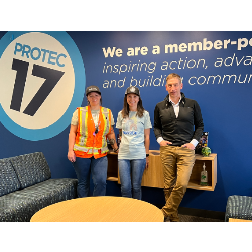 The 2024 Seattle Chapter Officers stand in front of the PROTEC17 wall at the office. From left to right is Jessica, Melissa, and Rob. They are all smiling and standing together.