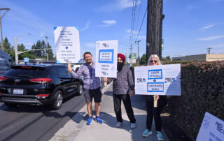 PROTEC17 union members/Department of Licensing workers at the Everett office, stand together on the side of the street with signs of support for their contract negotiations.